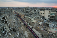 Warga Palestina duduk di meja besar yang dikelilingi puing-puing rumah dan bangunan yang hancur saat mereka berkumpul untuk berbuka puasa. (Dok. VOA Indonesia)